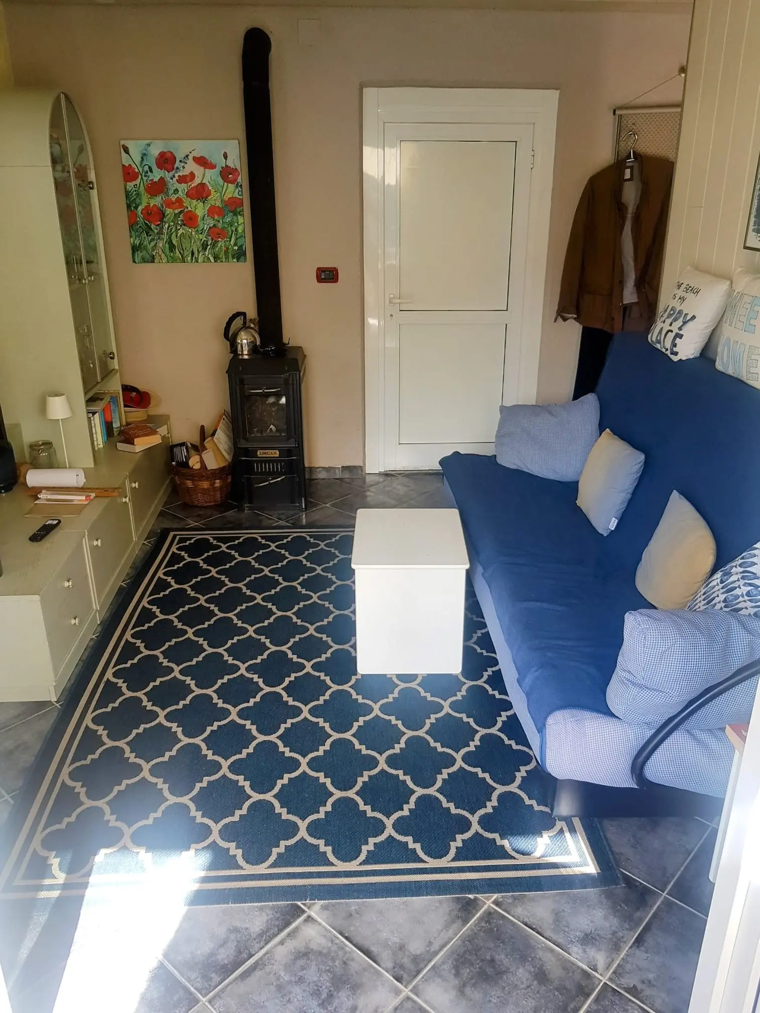 Aktueller Wohnbereich der Villa Carina mit Sofa und Kaminofen